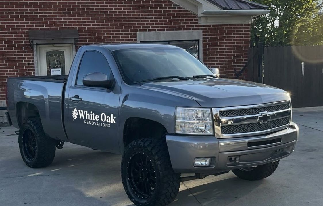 Grey pickup truck with the reversed White Oak Renovations mark on the door